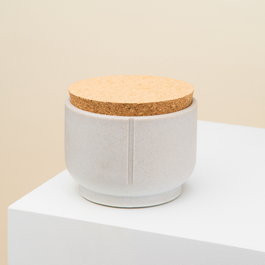 En grå godbidskrukke fra mærket Pino, den har et låg der er lavet i kork, så den slutter tæt