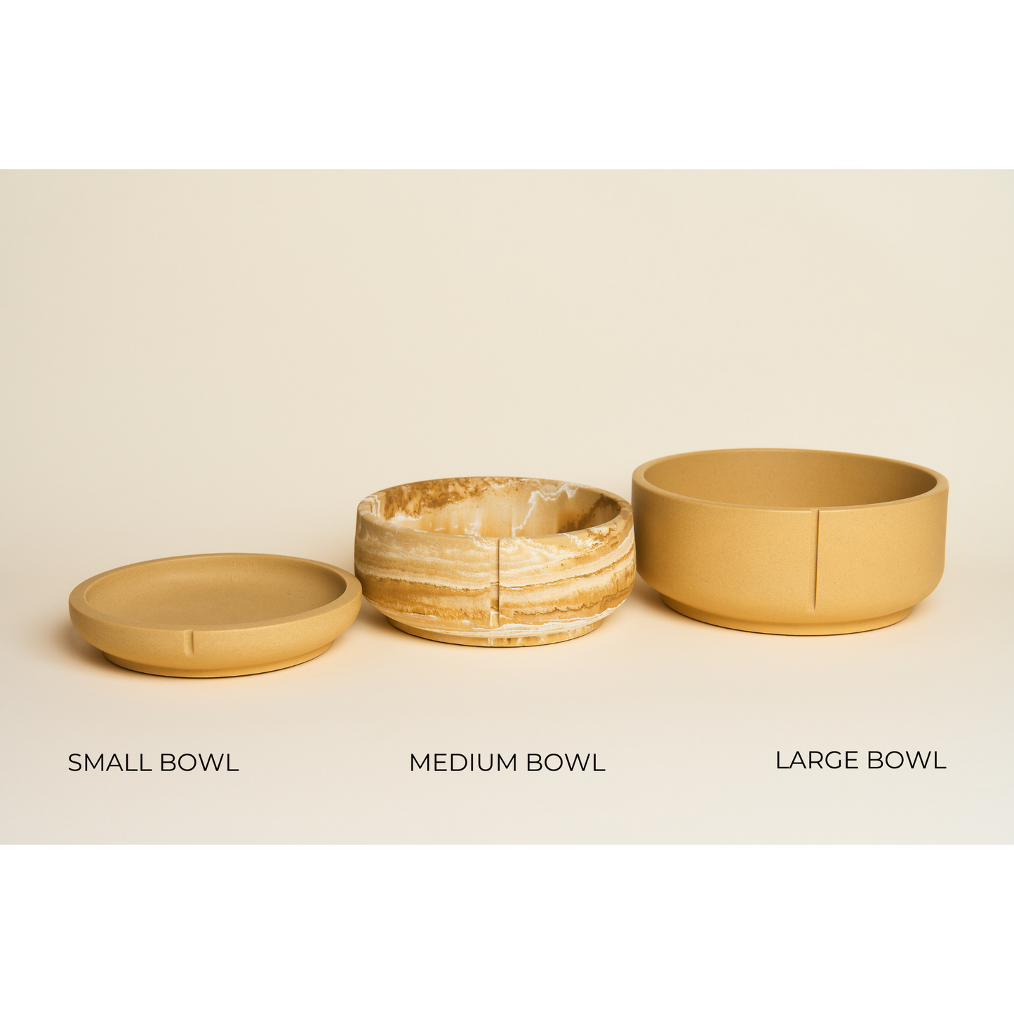 Tre hundeskåle i brun/gul, hvor den mellemste er marmoreret. De er stillet i størrelsesorden small, medium og large.
