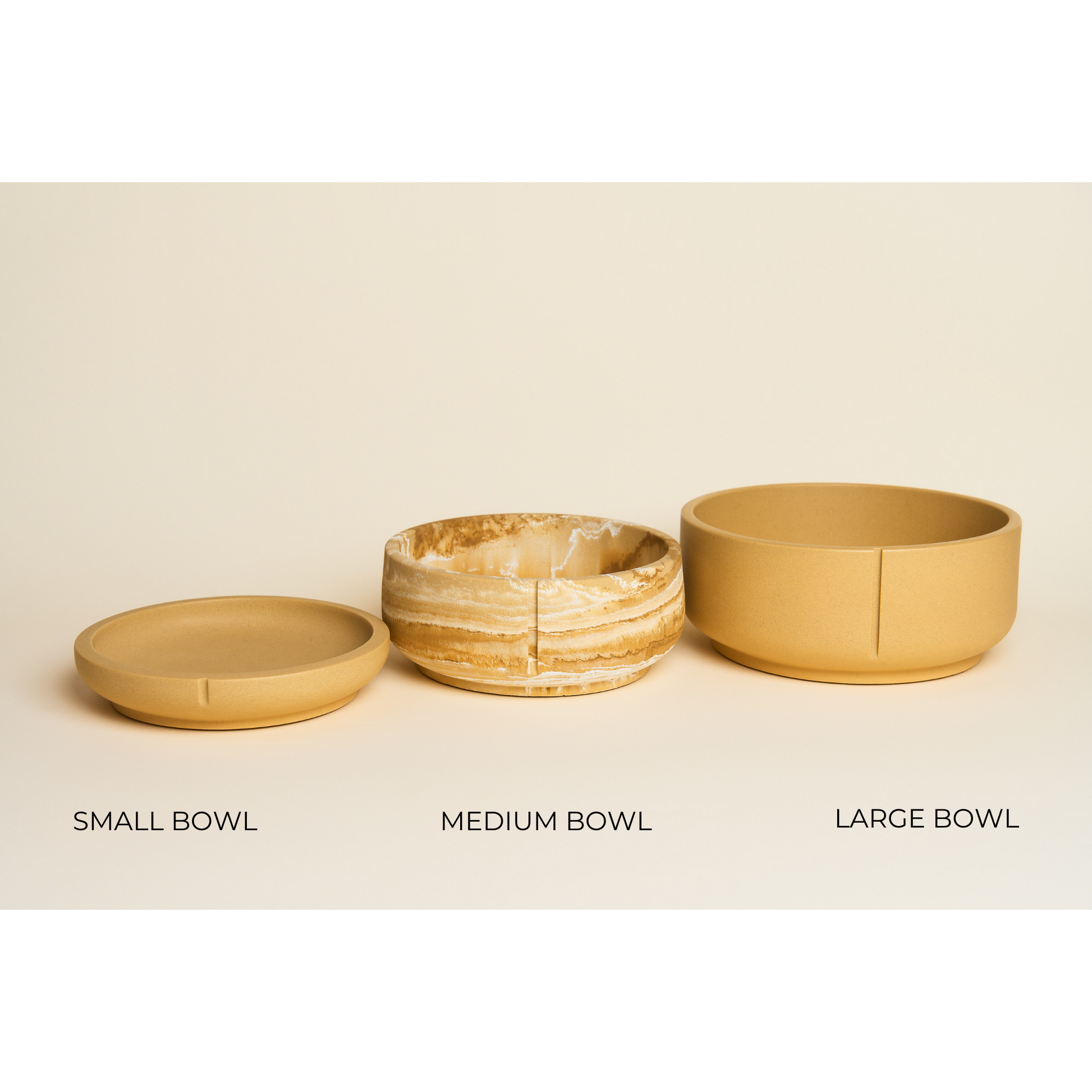 Tre hundeskåle i brun/gul, hvor den mellemste er marmoreret. De er stillet i størrelsesorden small, medium og large.