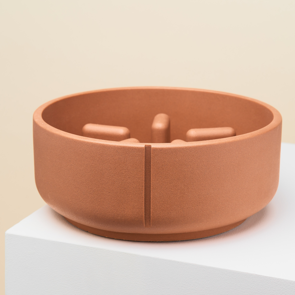 En rød slow feeder med 5 forhindringer nede i skålen. Skålen er en mellem størrelse og egnet til hunde.